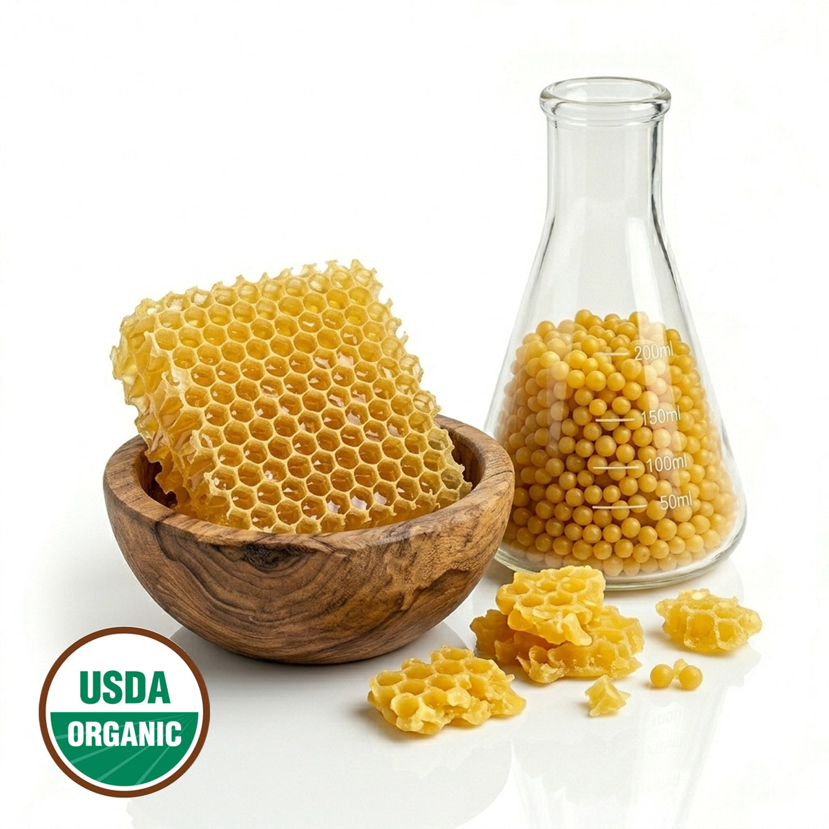 Honeycomb pieces in a wooden bowl and glass flas  with wax beads and a USDA Organic label on a white background
