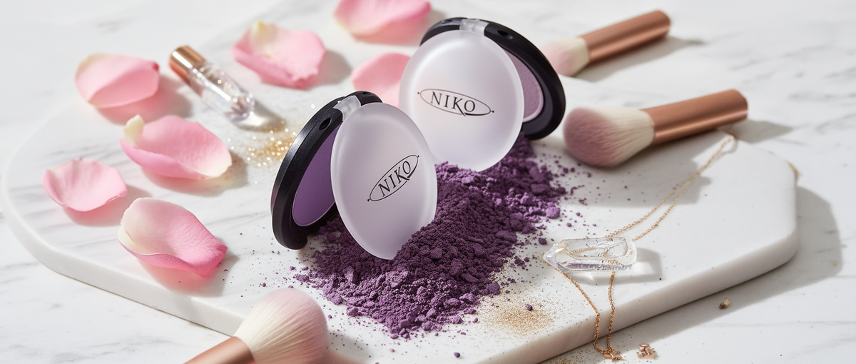 Two Eyeshadow compact cases, brushes, and pink petals on a marble surface with 'Niko' branding.