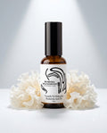 An amber glass bottle with a black cap and a white label reading 'Muskoka Wild Harvest Tremella Tri-Molecular Hyaluronic Acid 2%' and an image of Tremella mushroom  placed behind the bottle, centered on a whilte background with soft spotlights. 